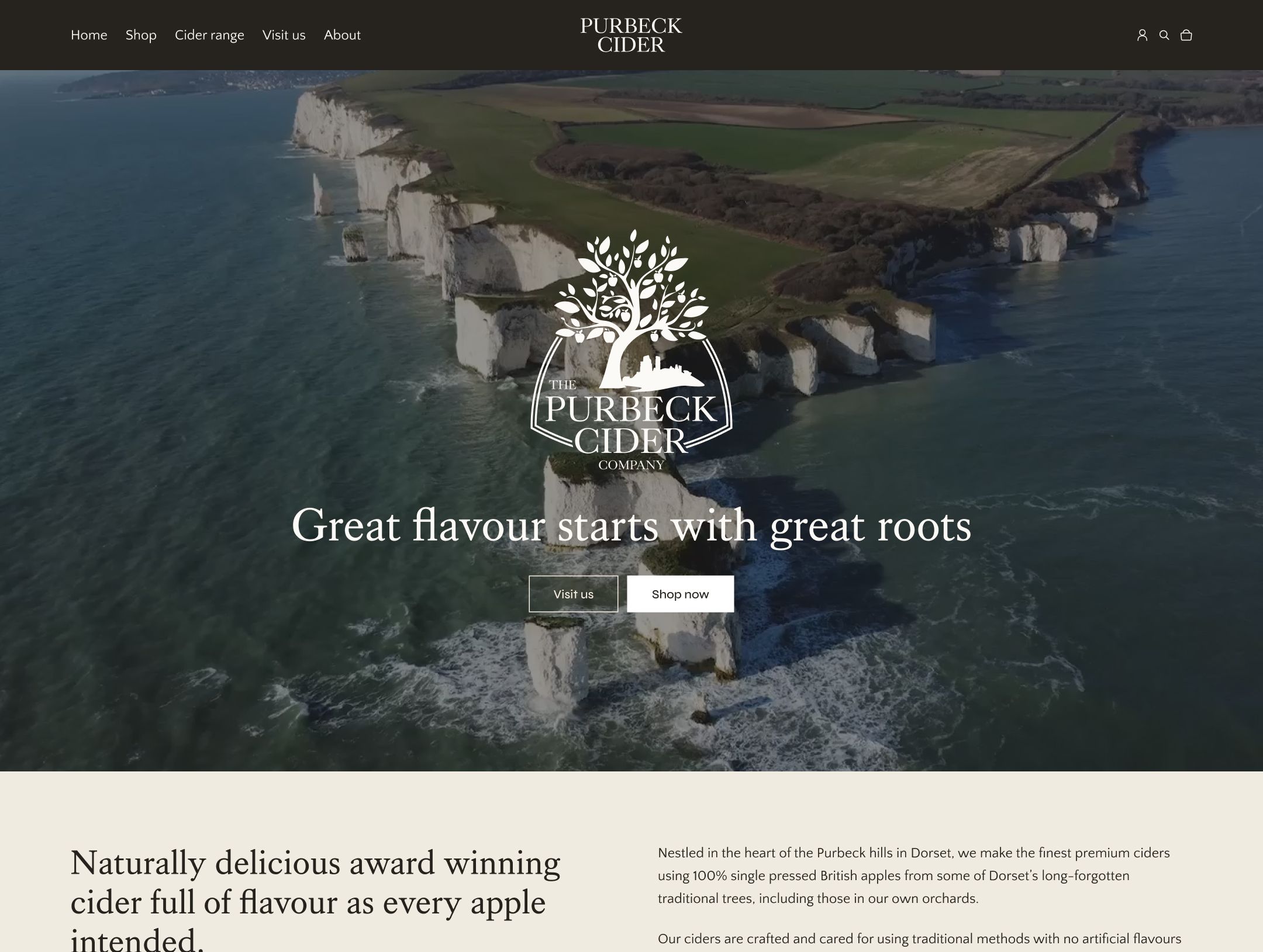 White chalk cliffs rise from turquoise sea with green fields beyond under overcast sky.