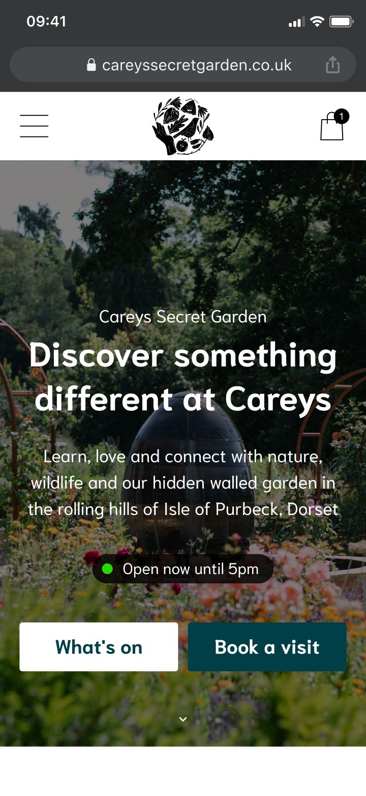 Website homepage for Careys Secret Garden showing a lush garden with flowers and greenery, with opening hours and booking.